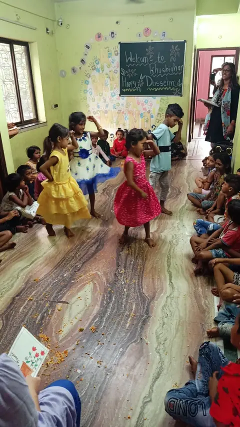 Bambine che ballano al centro della sala di Khushighar, fra i petali di fiori sul pavimento